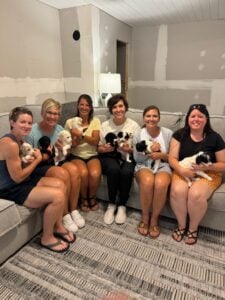 Ladies holding puppies with adult parents that have completed standard poodle health testing.